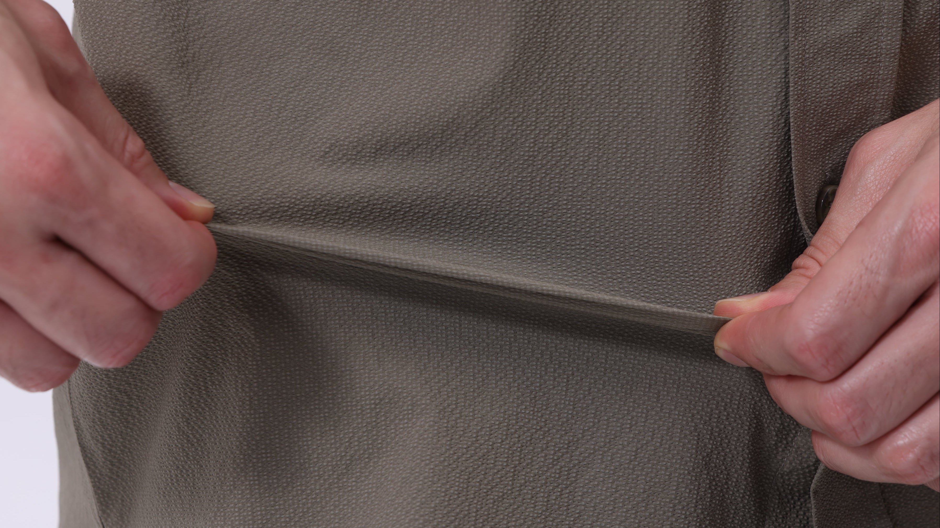 Person showing stretch fabric of new Infinity Stretch travel shirts.